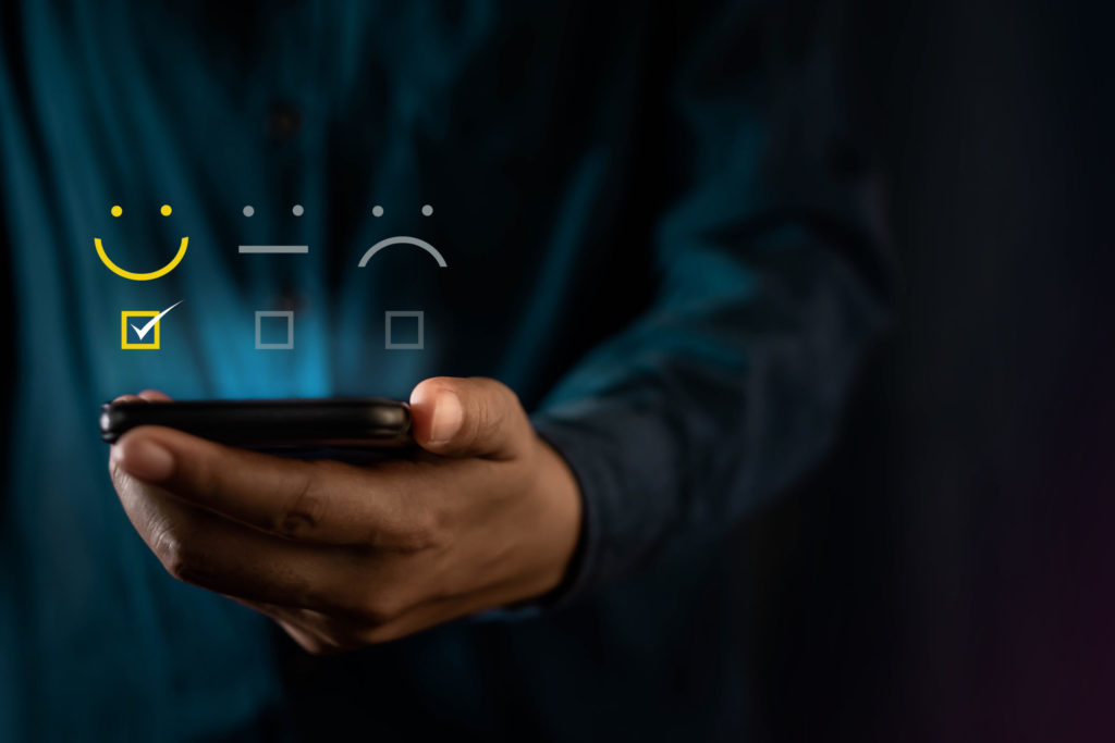 Customer Experiences Concept. Modern Man Giving a Smiling Emoticon Rating, Positive Review via Smartphone. Client's Satisfaction Surveys on Mobile Phone. Front View