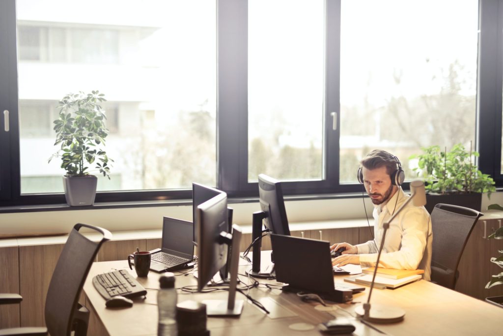 man with headphones facing computer monitor 845451 scaled 1